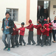 Volunteer leading a line of children in red jackets