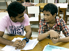 Volunteer assisting a young boy in a classroom