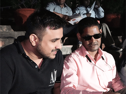 Project Quest event attendees including man with visual disability in pink shirt and supporter in black AU shirt at educational gathering